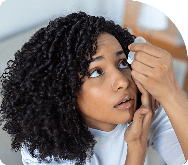 Woman curly hair applying eyedrops to eyes