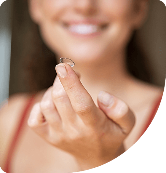 A smiling woman holding her contact lens.